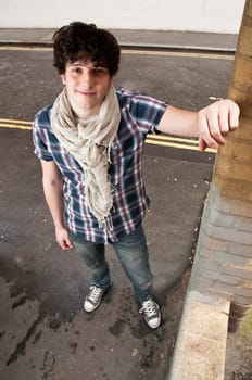 High angle full body street shot of young man smiling looking into the camera.