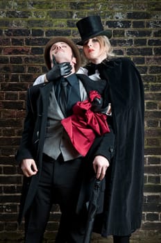 Fashion shot of woman  dressed as Jack the Ripper stealing man&#039 s handkerchief.
