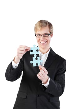Young blond handsome businessman in glasses holds two puzzle pieces