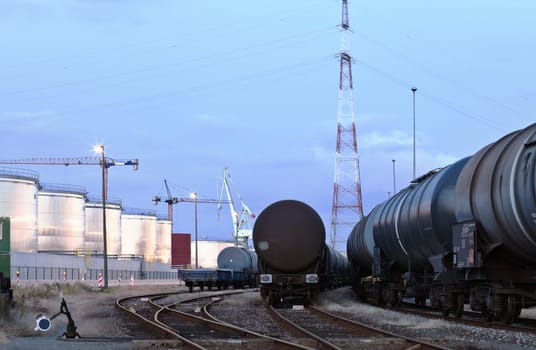 Oil tank cars standing on rail tracks in industrial area  twilight scene