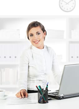 Young pretty businesswoman sitting at her workplace