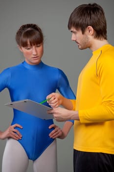 personal trainer giving instructions young woman in blue leotard