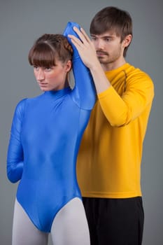 personal trainer helping woman in leotard with workout