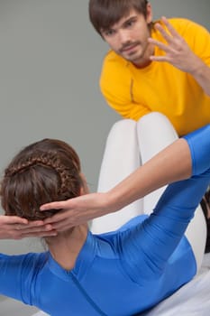 young woman doing sit-ups with personal trainer