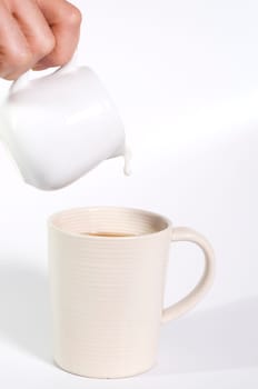 milk being poured out of jug into a cup