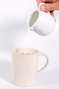 milk being poured out of jug into a cup