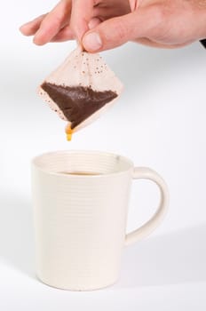 Tea bag being held out of cup