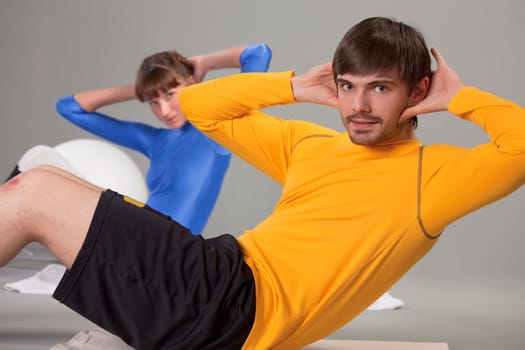 man and woman doing abdominal exercises on the ground