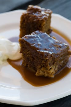 Sticky pudding and cream with silver spoon on wooden table