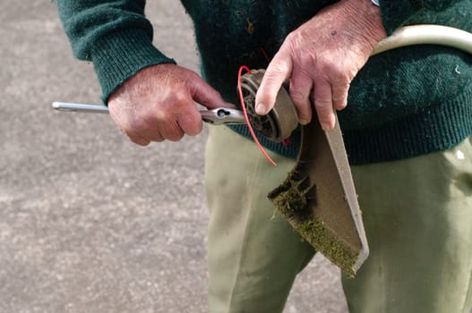 senior man fixing lawn trimmer