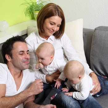Smiling,cheerful family with two babies - twins having fun with the children