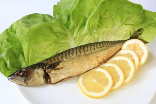 Smoked mackerel decorated with lemon on lettuce leaves