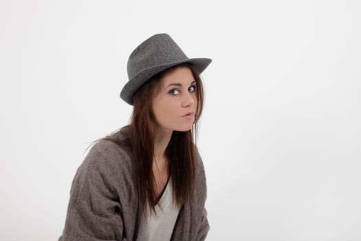 young woman in studio looking at the camera with grey hat
