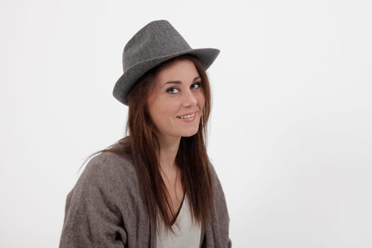 young woman in studio looking at the camera with grey hat