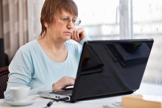 Elder woman working with laptop computer at home