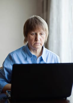 Elderly woman working with laptop computer at home