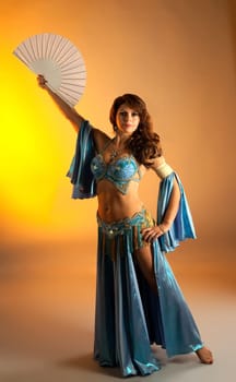 Mature woman in blue arabian costume belly dance with fan