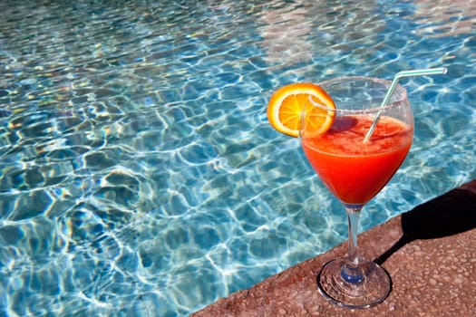 cocktail with a slice of orange at swimming pool