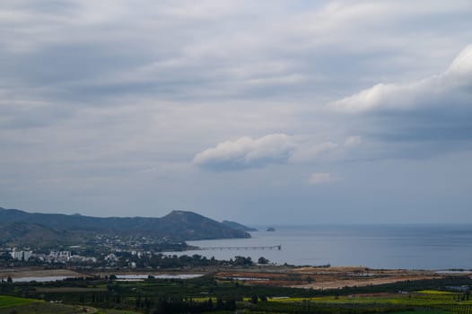 Serene landscape showcases lush greenery meeting calm sea under a cloudy sky, inviting a moment of reflection.