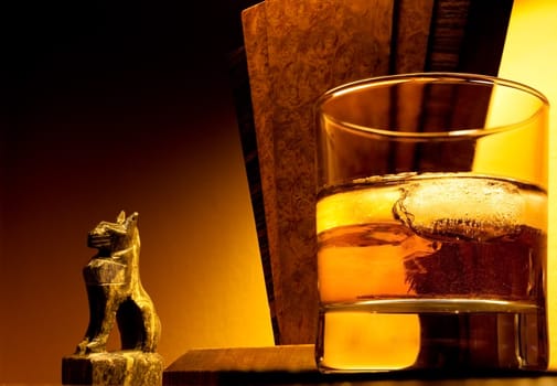Warm image of art deco lamp and ornament with glass of whiskey in foreground to support the concept of luxury and relaxation.