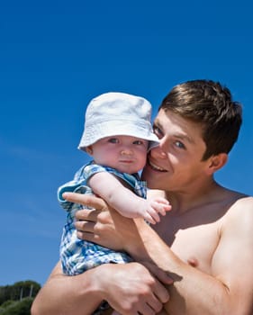 Young Father and2-3 month old baby son at beach for first time.