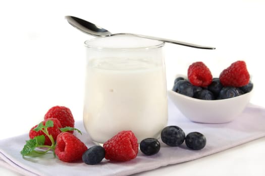 a jar of yogurt and fresh fruits against a white background