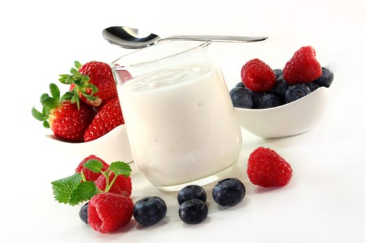 a jar of yogurt and fresh fruits against a white background