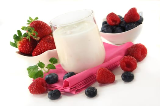 a jar of yogurt and fresh fruits against a white background
