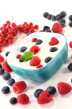 a jar of yogurt and fresh fruits against a white background