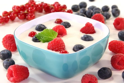 a jar of yogurt and fresh fruits against a white background