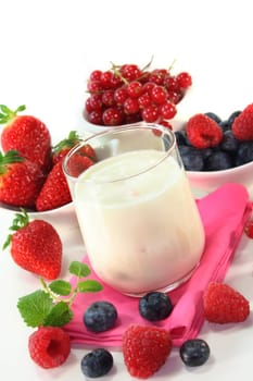 a jar of yogurt and fresh fruits against a white background