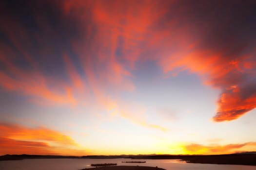 Atmospheric sky with red clouds after sunset at a lake