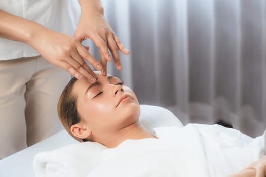 Caucasian woman enjoying relaxing anti-stress head massage and pampering facial beauty skin recreation leisure in dayspa modern light ambient at luxury resort or hotel spa salon. Quiescent