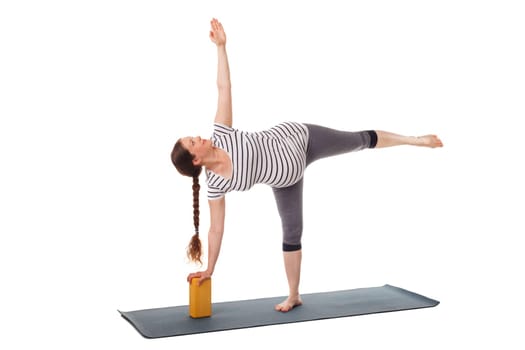 Pregnancy yoga exercise - pregnant woman doing asana virabhadrasana 3 - warrior pose with wooden block isolated on white background