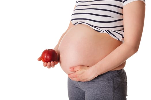 Healthy eating and diet during pregnancy concept - pregnant woman standing and holding red apple near her stomach isolated on white