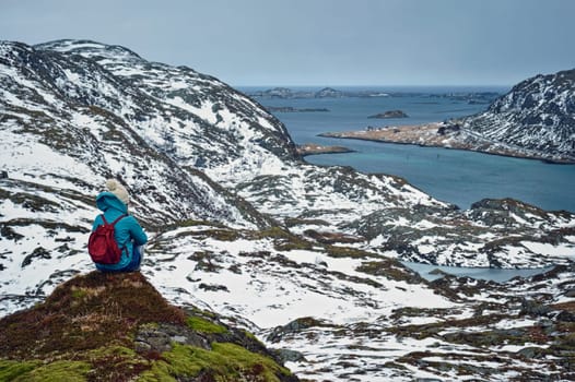 Woman tourist traveler enjoying a view of fjord in winter. Lofoten islands, Norway
