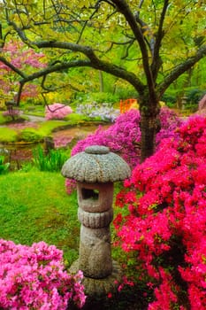 Stone lantern in Japanese garden with blooming flowers in Park Clingendael, The Hague, Netherlands