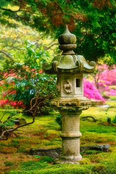 Stone lantern in Japanese garden with blooming flowers after rain in Park Clingendael, The Hague, Netherlands