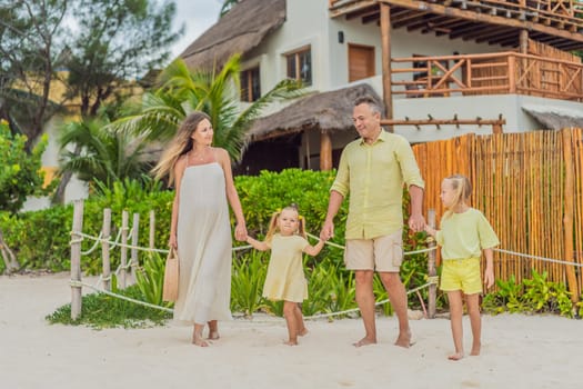 A joyful family, two girls, dad, and a pregnant mom, bask in tropical beach bliss, celebrating a radiant pregnancy amidst paradise.