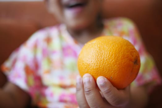child holding a slice of orange fruit .