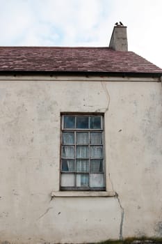 an old decaying house front window in ireland with crows
