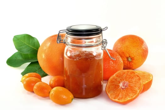 a jar of jam and fresh fruits against a white background