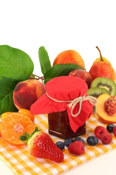 a jar of jam and fresh fruits against a white background