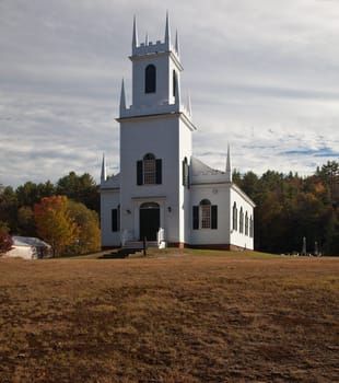 Autumnal shot of the typical Vermont church in fall as the bright trees turn orange and red