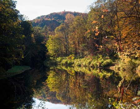 Autumn scene in Vermont as leaves are reflected in calm river