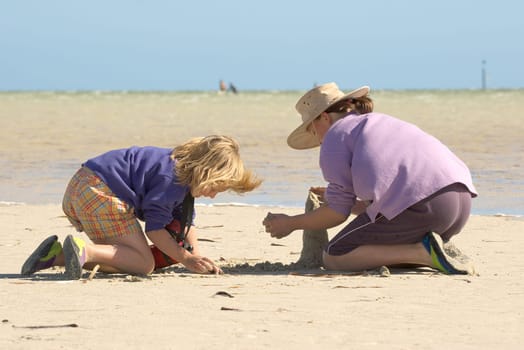 two girls sitting on the beach building sandcastles 2 of 4 in series