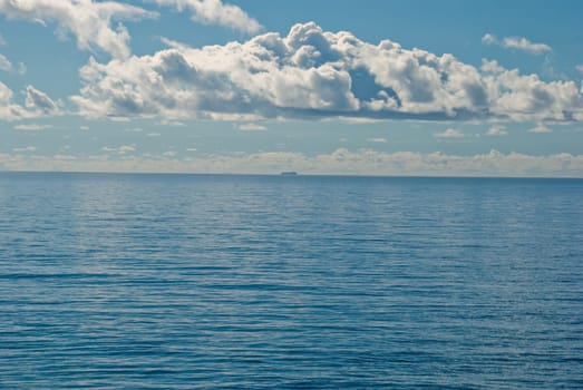a distant ship on the flat and calm deep blue tropical ocean