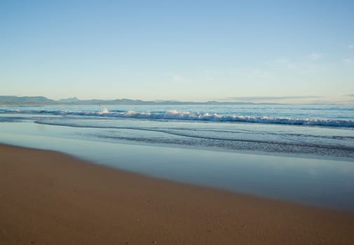 a nice beach scene with gentle waves reaching the sand