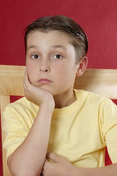 Seated boy resting his head on one hand and looking toward the viewer.