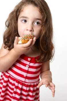 Little girl in a light pink and red striped dress eats a tasty pink iced decorated doughnut